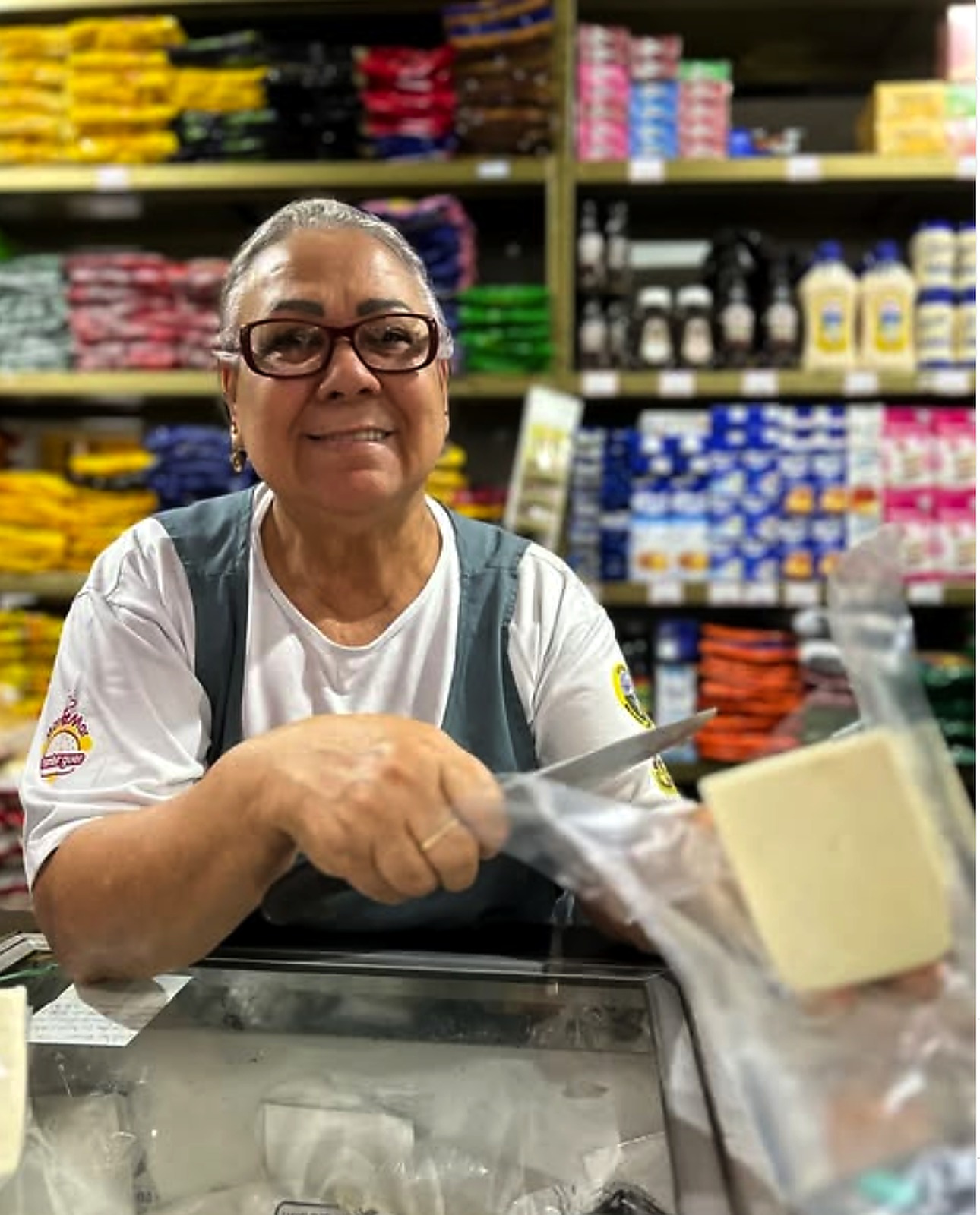 Comerciante cortando queijo no balcão